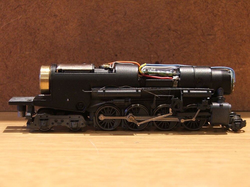 An N scale steam locomotive with its body removed, showing a decoder wired into the top of the mechanism with coloured wires.